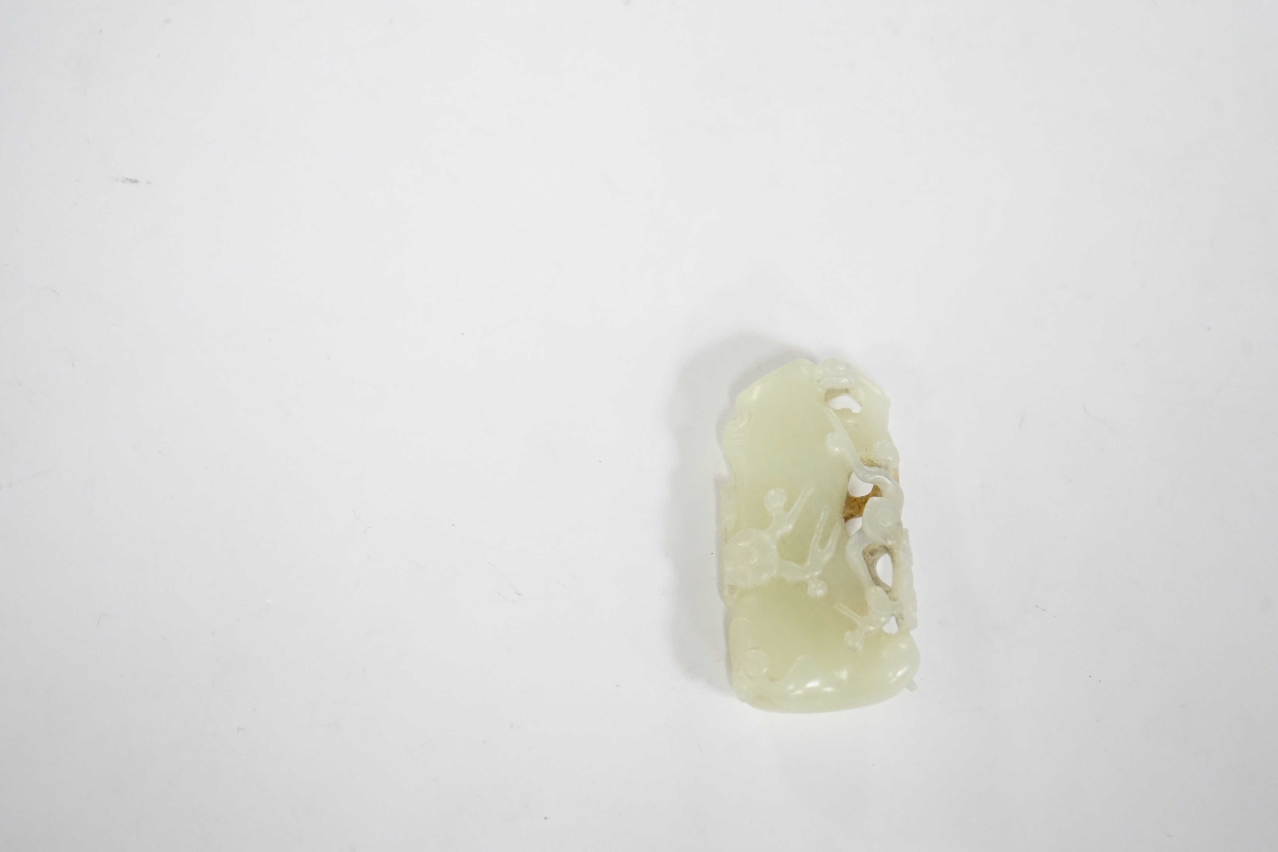 A Chinese pale celadon and russet jade carving of a prunus bough, 5.4cm